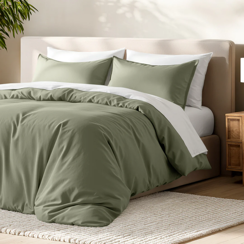 Neatly made bed with sage green bedding