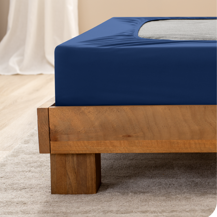 Box spring with a tan cover on a wood bed frame