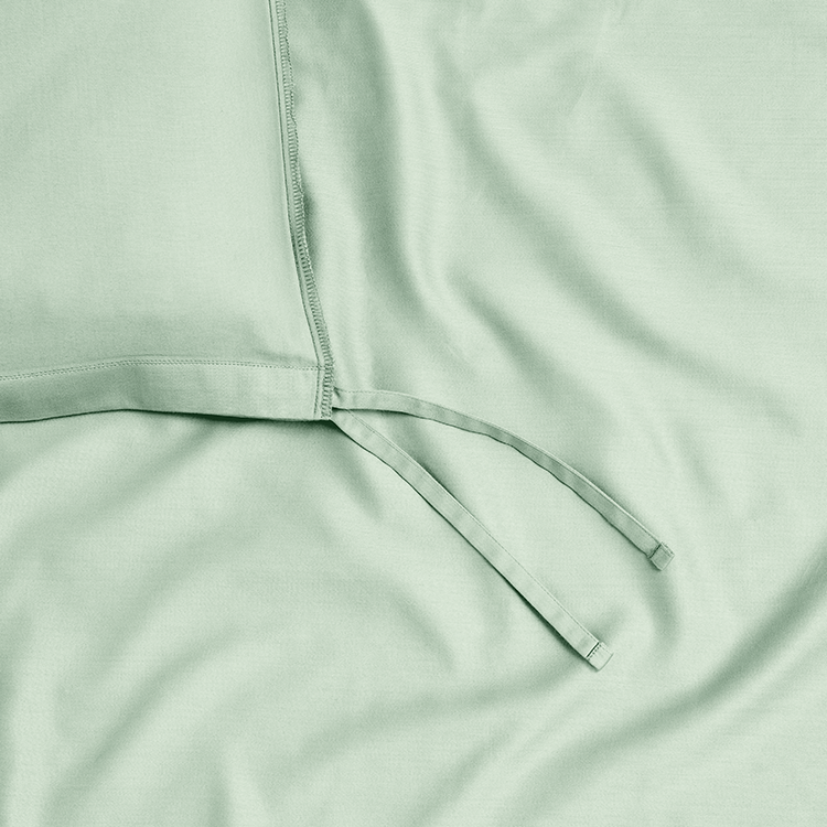 Closeup of sage green Organic Cotton Sateen Duvet Cover Set fabric texture, draped