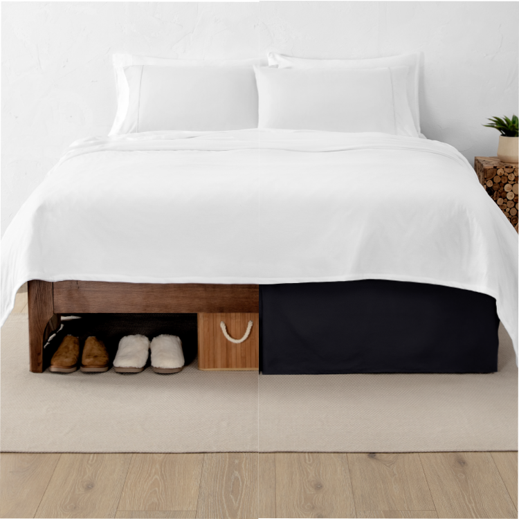 Bed with a white bed skirt on a wood frame in a dark bedroom