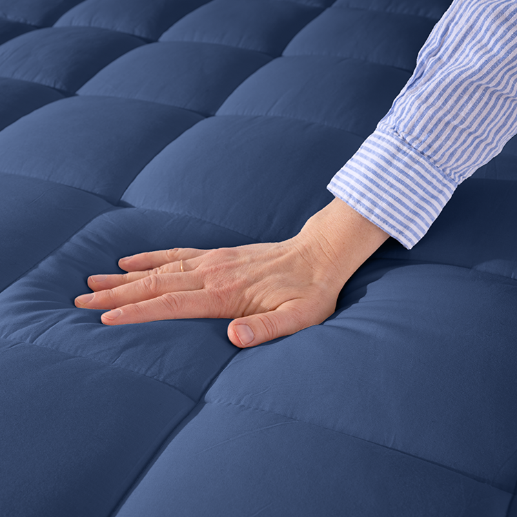 Hand pressing on navy blue fabric backing of Cotton Top Mattress Pad