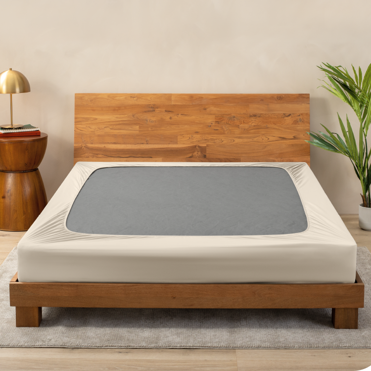 Box spring with a tan cover on a wood bed frame