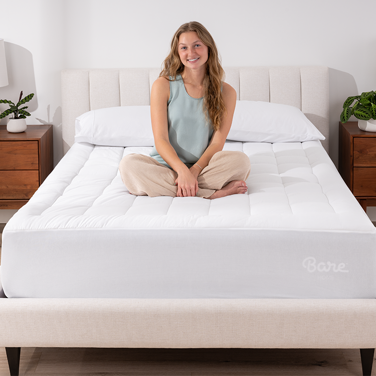 Woman sitting on a bed with white Cotton Top Mattress Pad