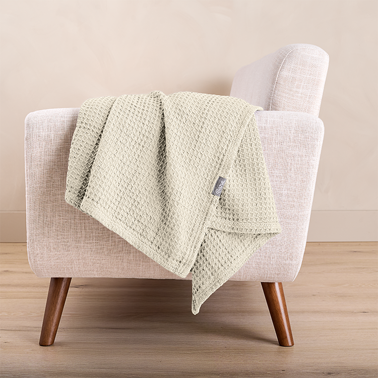 Folded white waffle cotton blanket draped on a chair