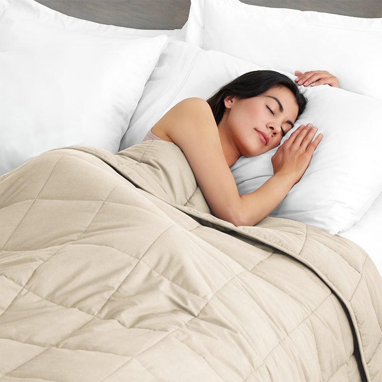 Person sleeping in bed with a tan weighted blanket