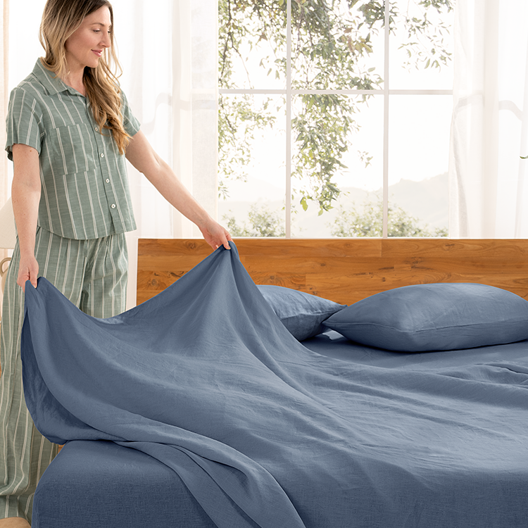 Woman making a bed with blue European Linen Sheet Set