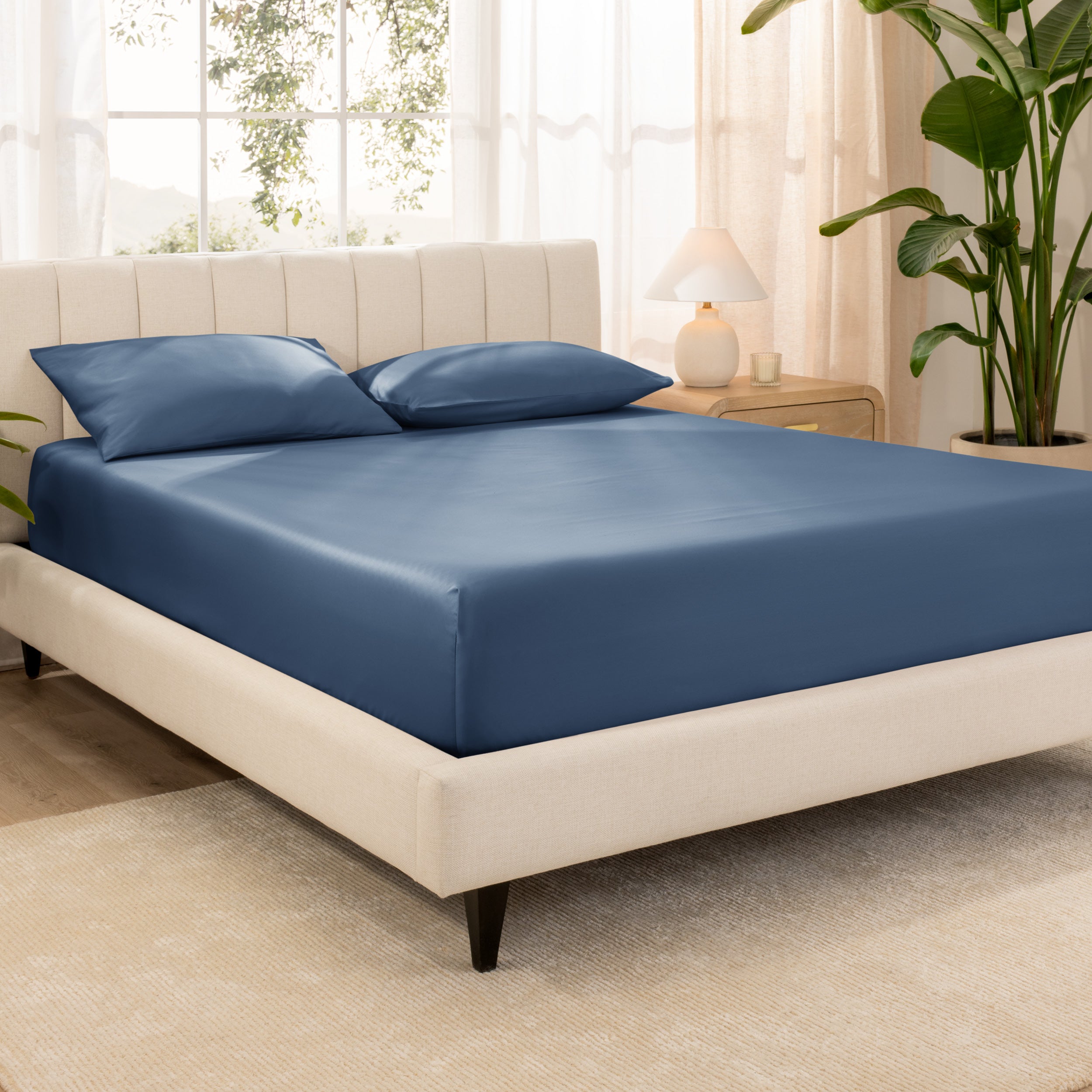 A bed made with an organic cotton sateen fitted sheet and matching pillowcases on pillows