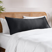Body pillowcase on a pillow set on a bed with a wicker headboard and a plant in the corner.