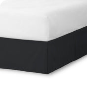 The corner of a bed skirt on a bed frame