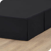 A box spring with a bed skirt on it