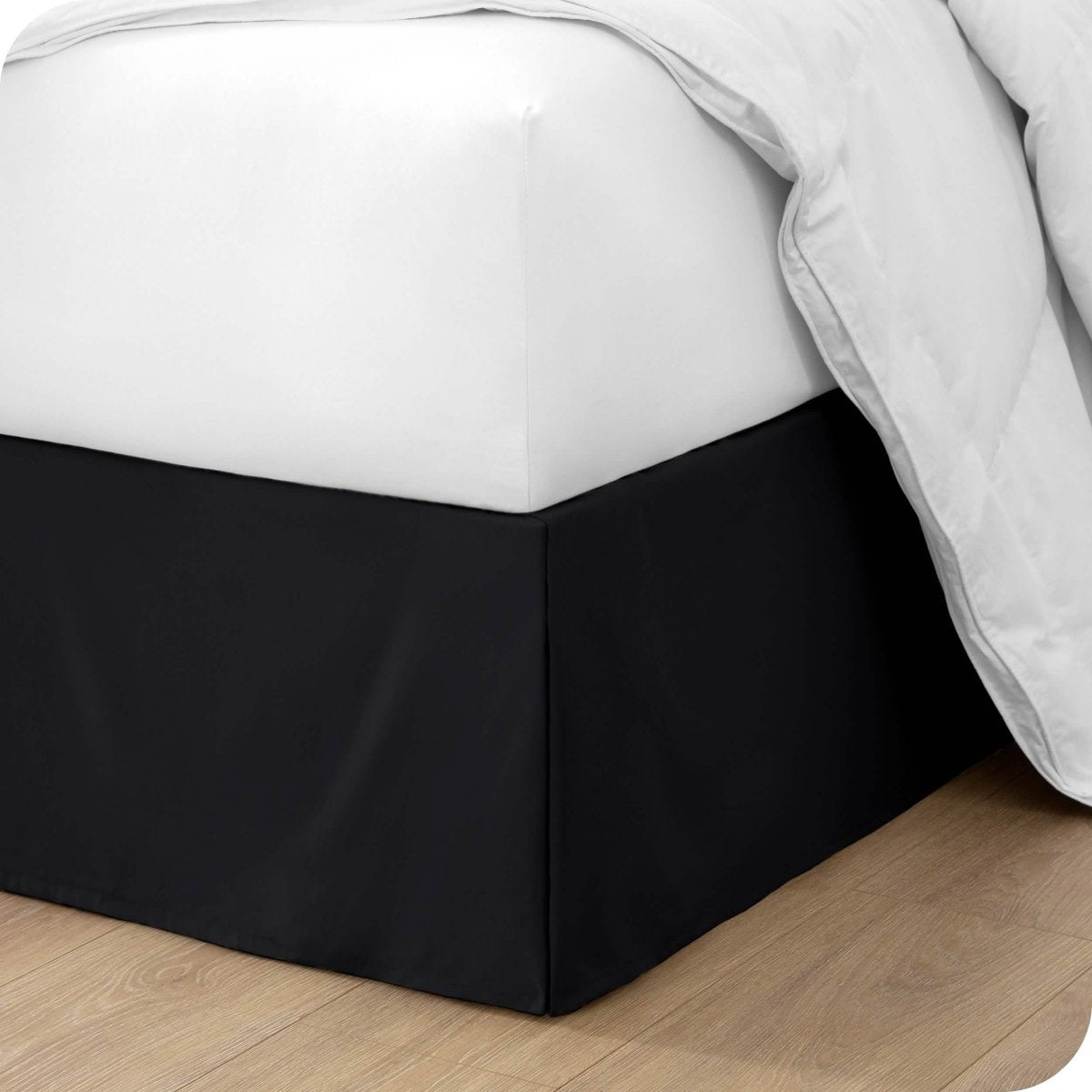 The corner of a bed with a bed skirt and comforter on it