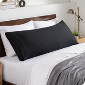 A body pillowcase on a pillow set against a headboard