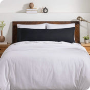 A body pillow cover on a pillow on a bed with other pillows and a duvet cover