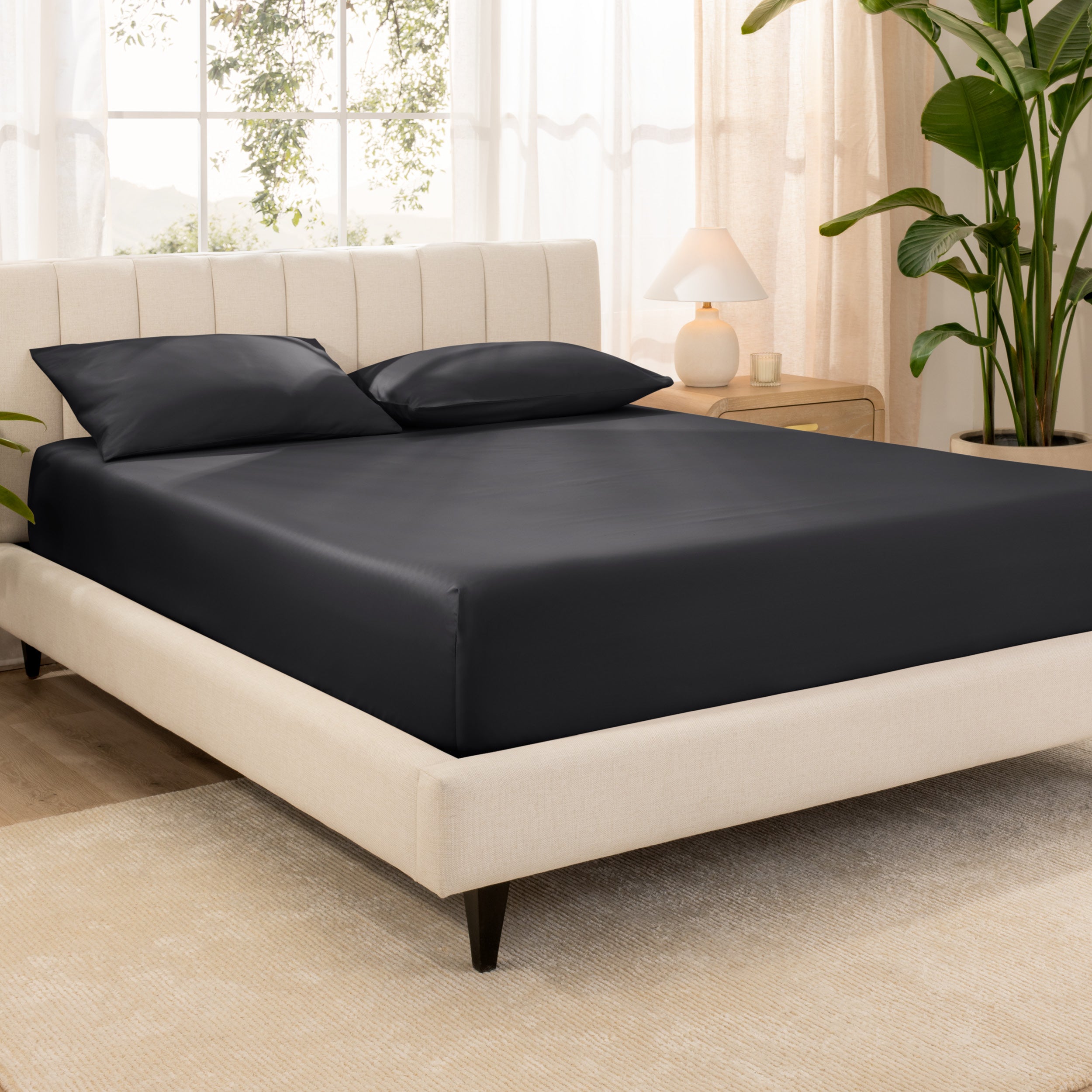 A bed made with an organic cotton sateen fitted sheet and matching pillowcases on pillows