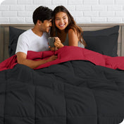 A couple sitting in a bed made with a reversible comforter and sheet set