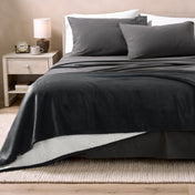 Bed with grey sheets and a sherpa blanket