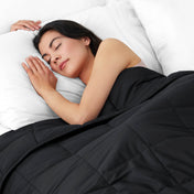 Woman sleeping peacefully under a weighted blanket with white pillows