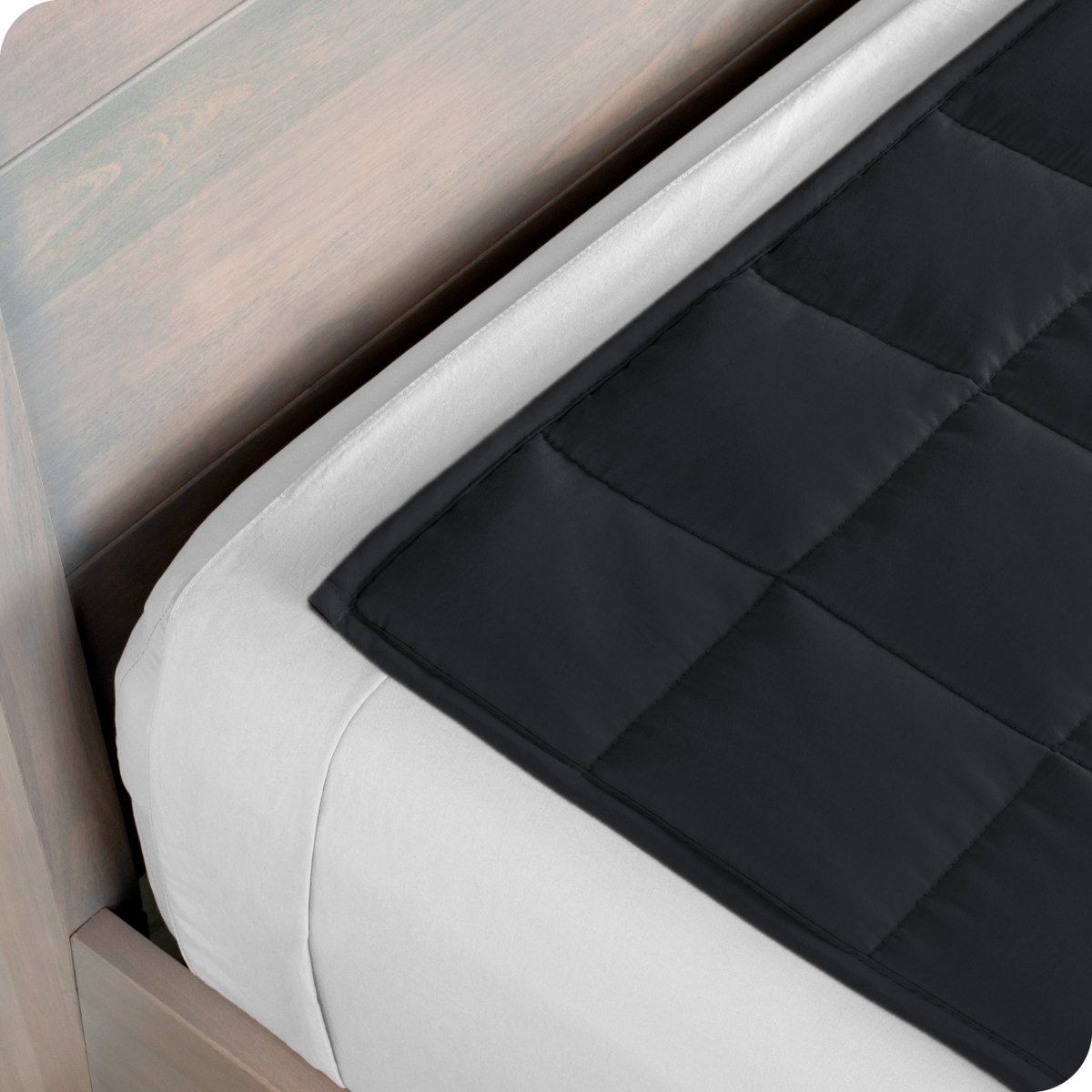 Close up of a weighted blanket on top of a bed made with white sheets