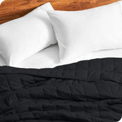 Close up of a weighted blanket on a bed next to pillows