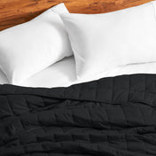 Cotton weighted blanket on a bed with white pillows against a wooden headboard.