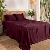 Bamboo sheets on a bed in a bedroom with plants and a lamp.
