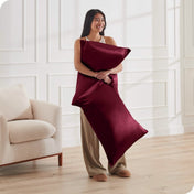 A woman standing while holding pillows with silk pillowcases on them