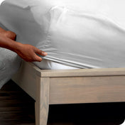 Person adjusting a fitted sheet on a mattress