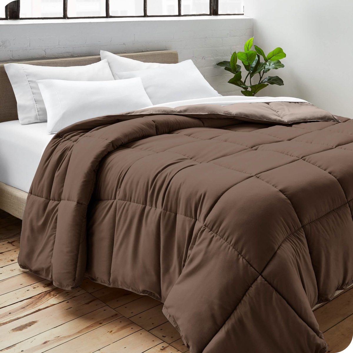 Close up of a comforter on a bed folded over itself. There are also 4 pillows on the bed.
