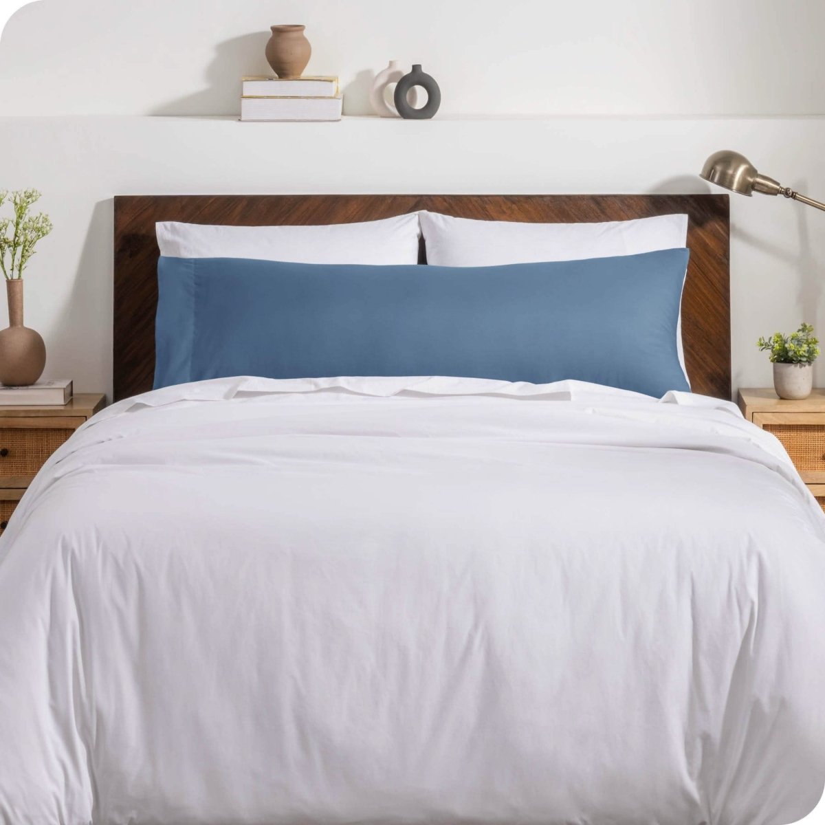 A body pillow cover on a pillow on a bed with other pillows and a duvet cover