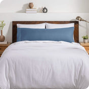 A body pillow cover on a pillow on a bed with other pillows and a duvet cover
