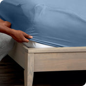 Person adjusting a fitted sheet on a mattress