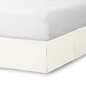 The corner of a bed skirt on a bed frame