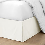 The corner of a bed with a bed skirt and comforter on it