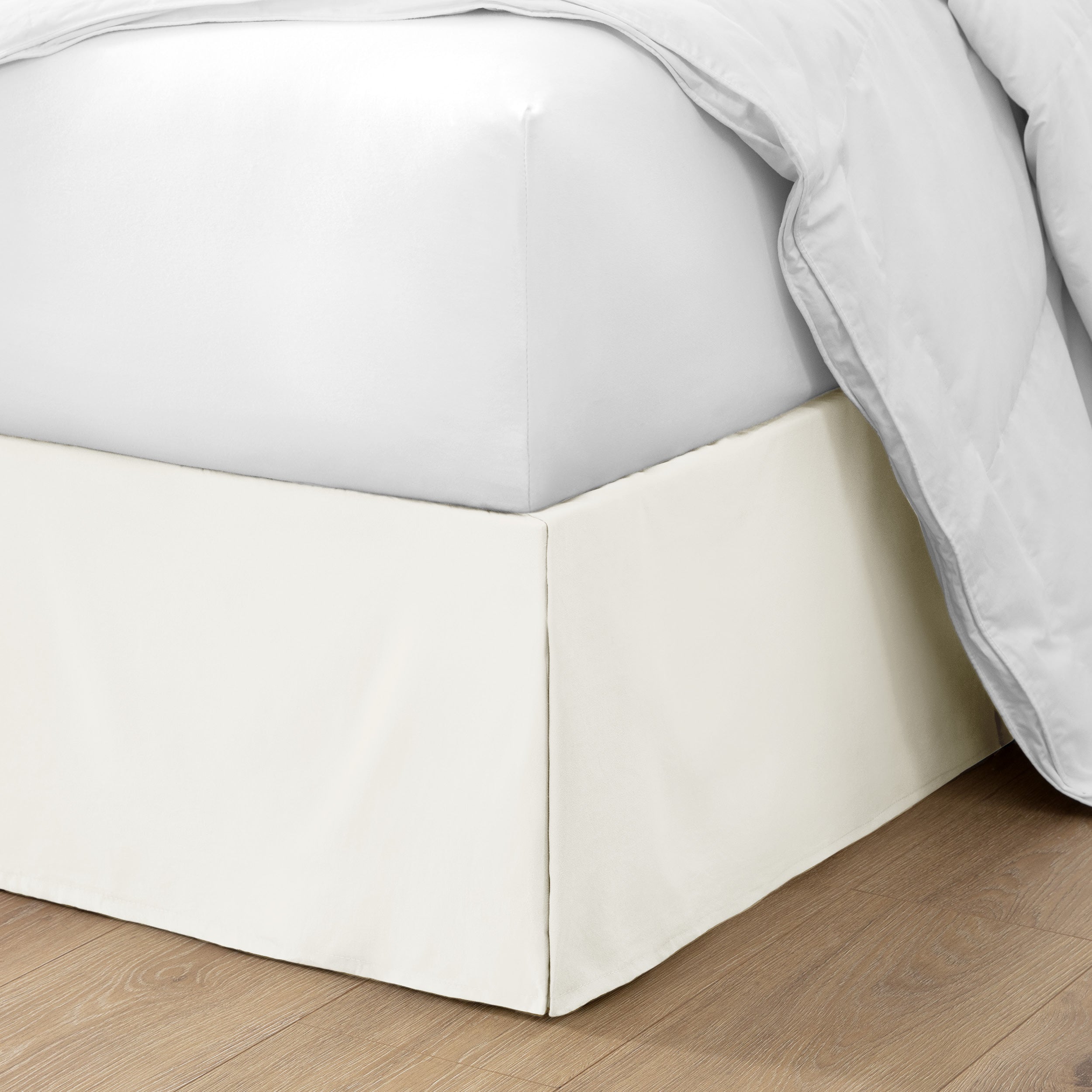 The corner of a bed with a bed skirt and comforter on it