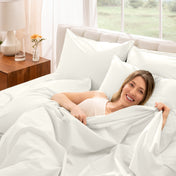 A woman is lying on a bed make with percale sheets and pillowcases