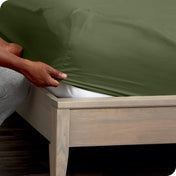 Person adjusting a fitted sheet on a mattress