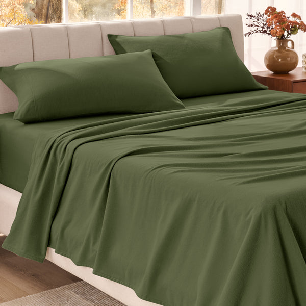 Bed sheets on a neatly made bed in a bright bedroom with large windows.