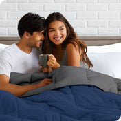 A couple sitting in bed with a reversible comforter over them