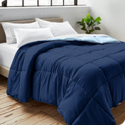 Close up of a comforter on a bed folded over itself. There are also 4 pillows on the bed.