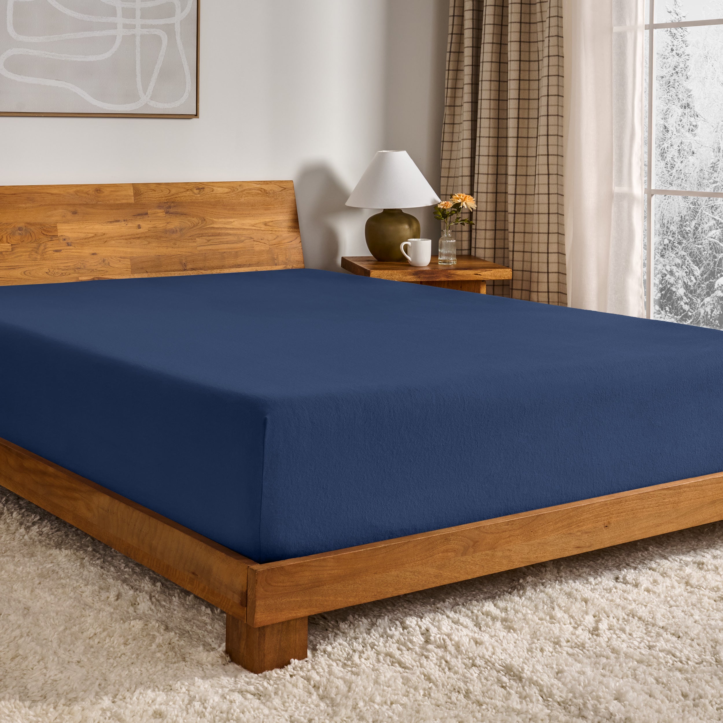 Blue fitted sheet on a wooden bed in a bedroom setting