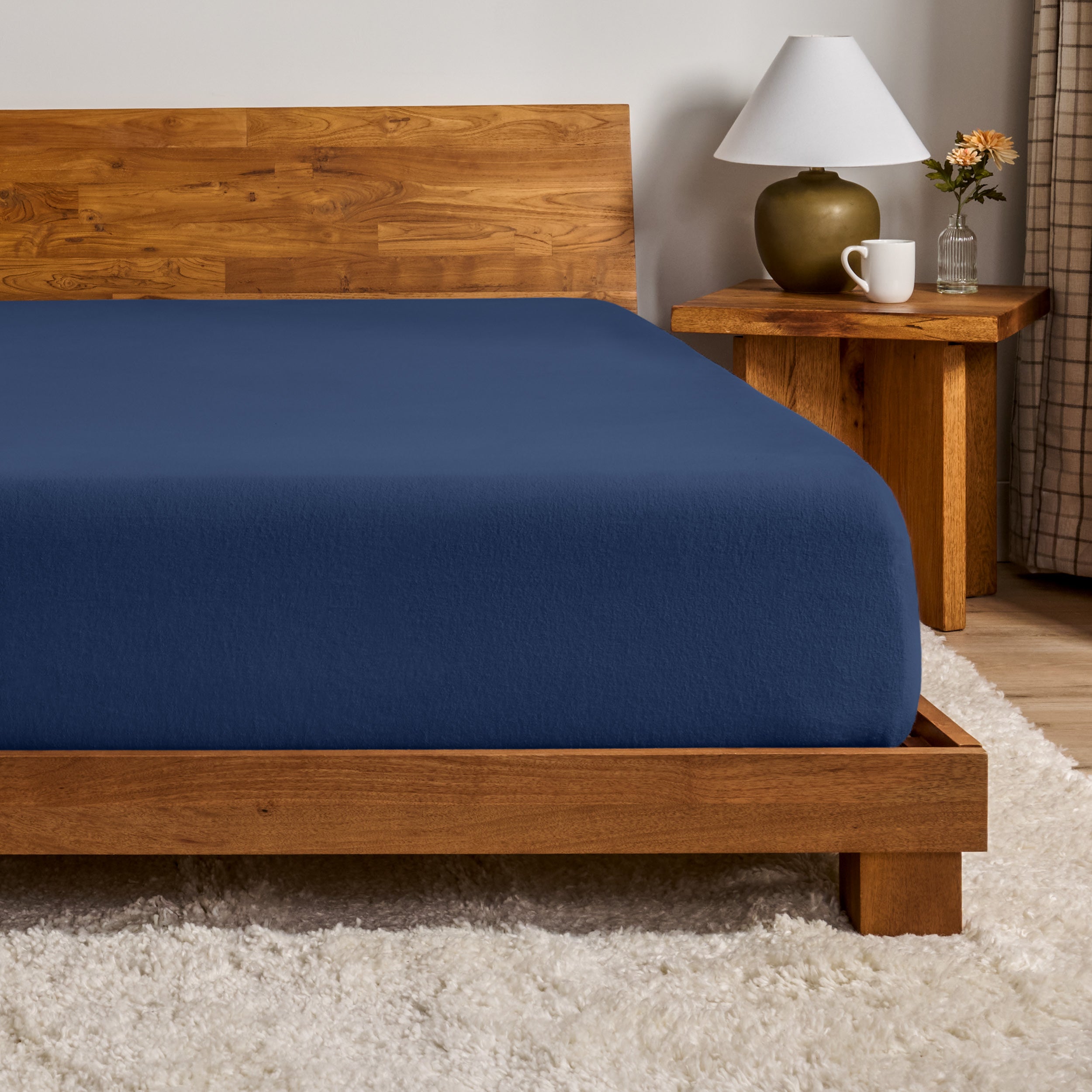 A flannel fitted sheet on a mattress with a wooden bed frame