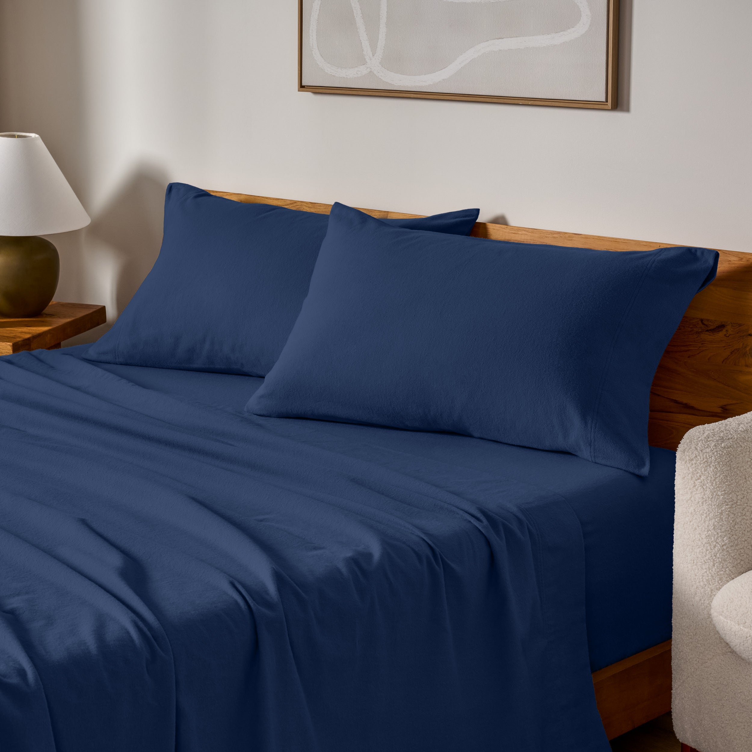Cotton flannel sheets and pillows on a wooden bed in a bedroom setting.