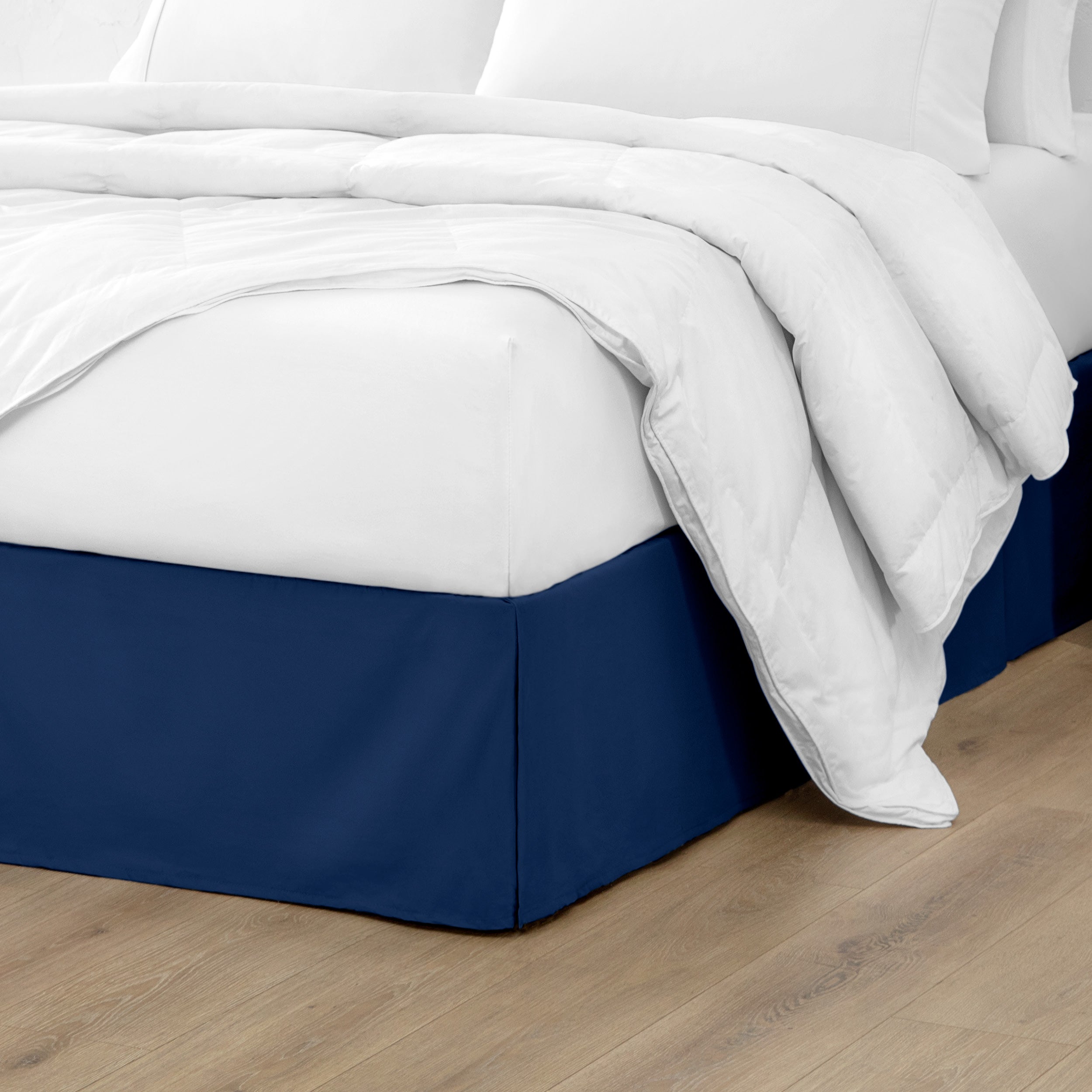 A modern bed with a microfiber bed skirt with pleats on the corners and midway on each side