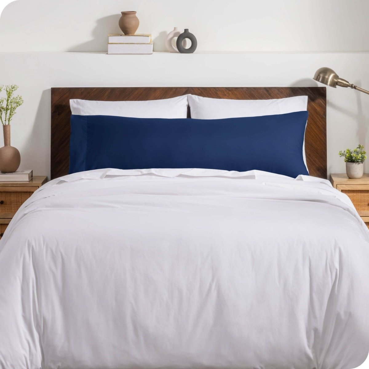 A body pillow cover on a pillow on a bed with other pillows and a duvet cover
