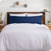 A body pillow cover on a pillow on a bed with other pillows and a duvet cover