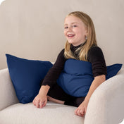 A child sitting while holding a microfiber pillowcase covered pillow