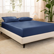 A bed made with an organic cotton sateen fitted sheet and matching pillowcases on pillows