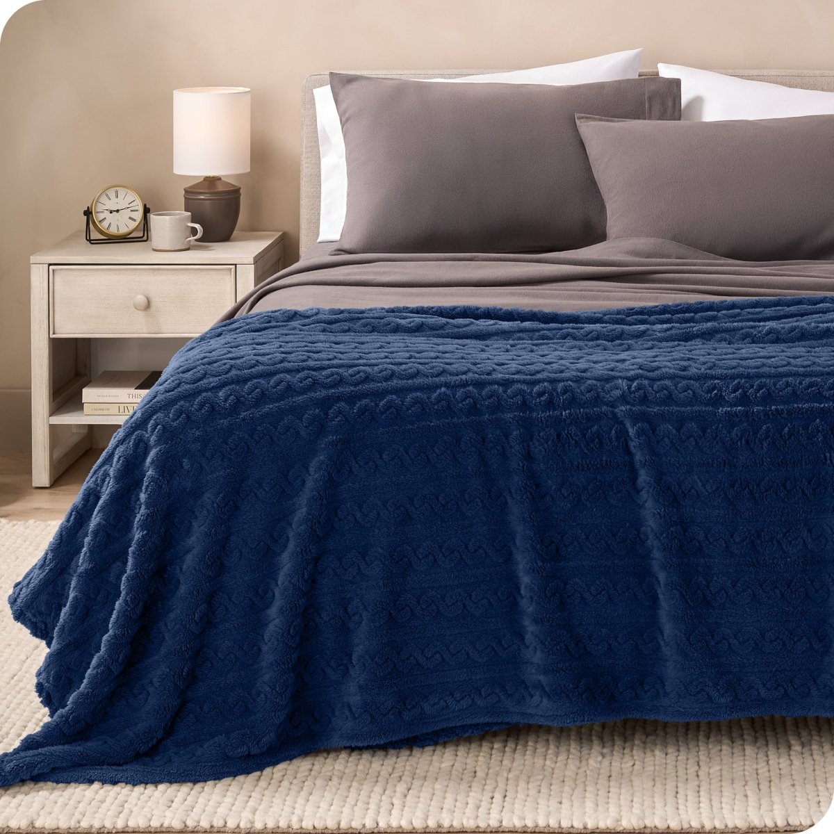 A textured sherpa blanket draped over the end and side of a bed