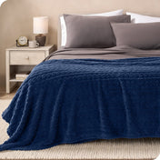 A textured sherpa blanket draped over the end and side of a bed