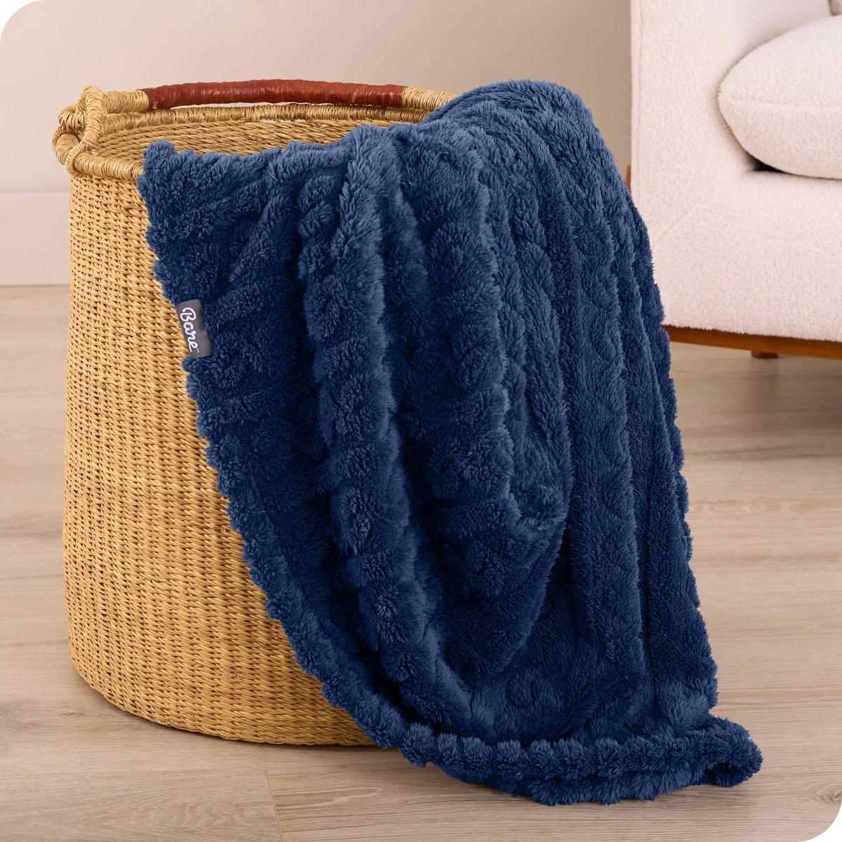 A sherpa blanket is hanging over the edge of a woven hamper